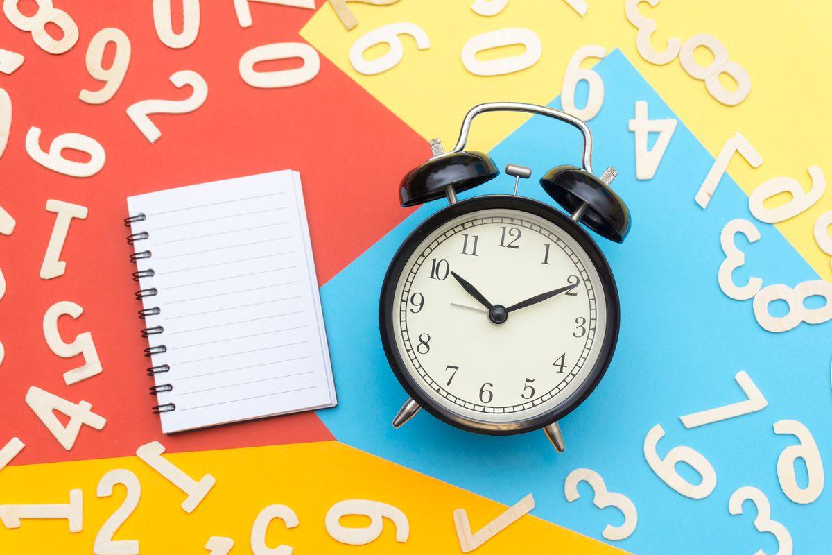 A clock and notebook on a colorful background
