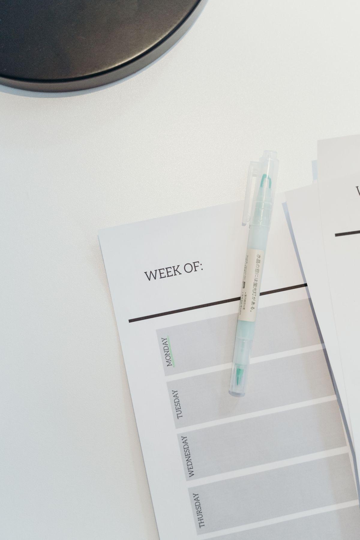 A weekly planner and pen on a clean desk